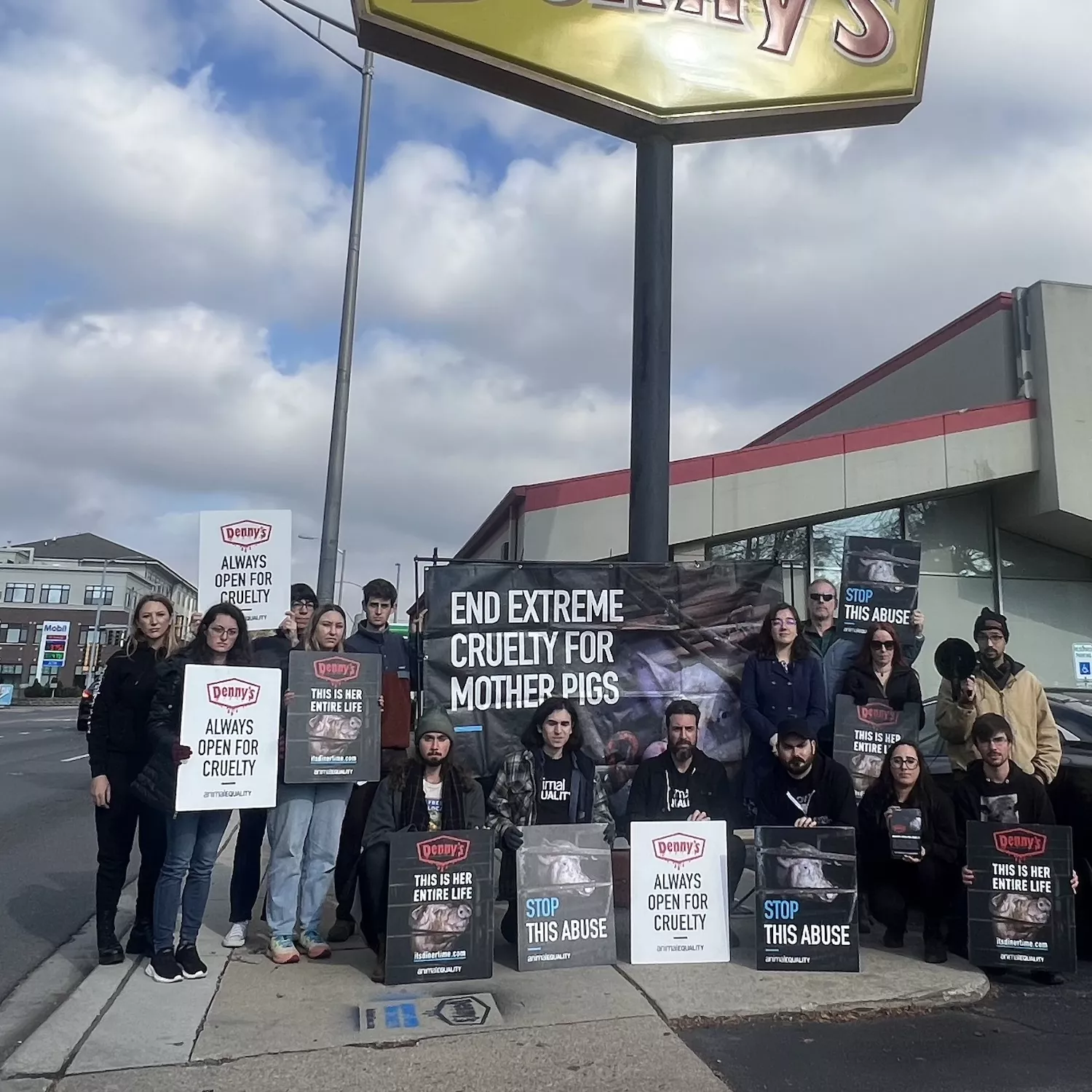 Protesters with signs outside of a Denny's restaurant calling for an end to cages.